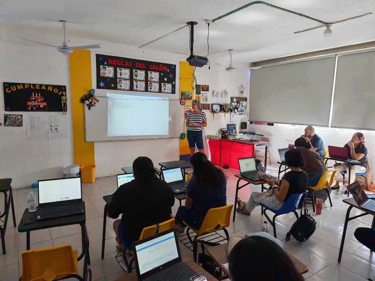 Teacher training, laptops open, real classroom.